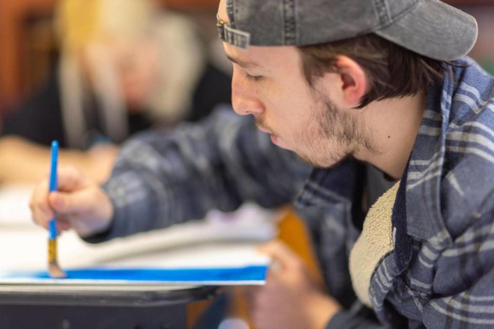 Joe Crace, a junior at the David School in David, Ky., paints during art class on Thursday, Feb. 8, 2024.. Located in Floyd County, the school was founded in the early 1970s as an alternative for students at risk of dropping out of public schools.