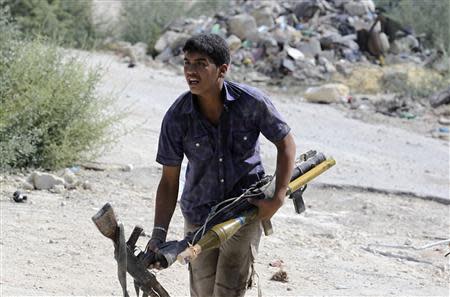 A Free Syrian Army fighter carries weapons of his fellow fighters who were caught under sniper fire on the front line in Aleppo's Sheikh Saeed neighbourhood September 21, 2013. REUTERS/Molhem Barakat