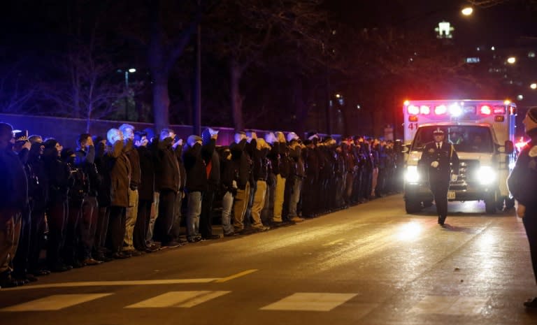 Firefighters and police salute as the ambulance carrying the remains of Chicago Police officer Samuel Jimenez arrive at the Cook County Medical Examiner's office