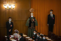 FILE - A delegate in ethnic minority dress stands before a session of China's National People's Congress (NPC) at the Great Hall of the People in Beijing, Friday, March 10, 2023. The National People's Congress is largely ceremonial in that it doesn't have any real power to decide on legislation. The deputies do vote, but it's become a unanimous or near-unanimous formalizing of decisions that have been made by Communist Party leaders behind closed doors. (AP Photo/Mark Schiefelbein, File)