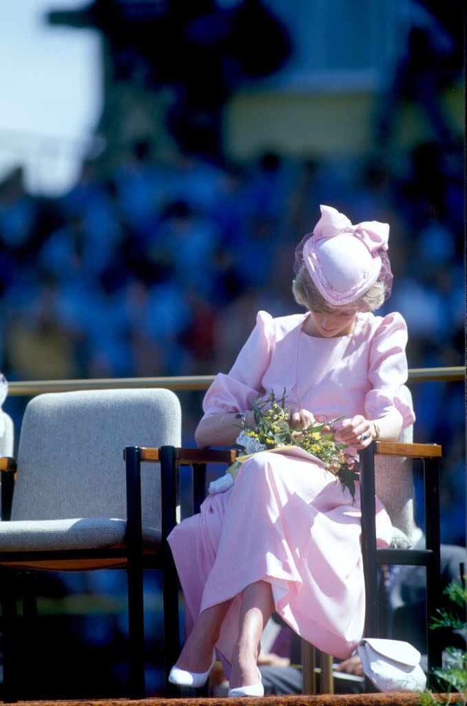 <p>Princess Diana gazes down at a floral arrangement while wearing a pink Catherine Walker dress with John Boyd hat.</p>