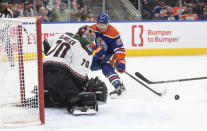 Arizona Coyotes goalie Karel Vejmelka (70) makes a save on Edmonton Oilers' Warren Foegele (37) during the second period of an NHL hockey game Friday, April 12, 2024, in Edmonton, Alberta. (Jason Franson/The Canadian Press via AP)