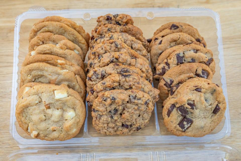 White-chocolate chunk cookies, oatmeal raisin cookies, and chocolate chunk cookies in three rows in a plastic container