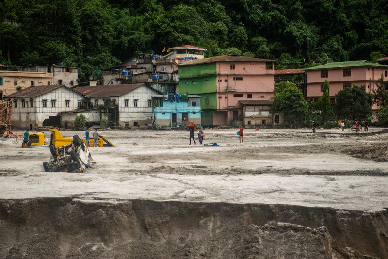 People walk along the area affected by flood at Golitar, in Singtam