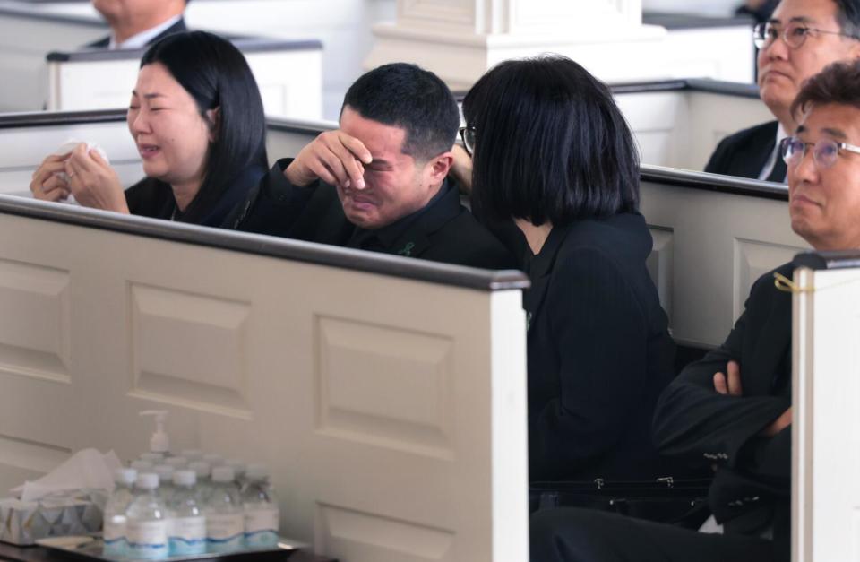 Mourners wearing black weep as they sit in pews during a funeral service