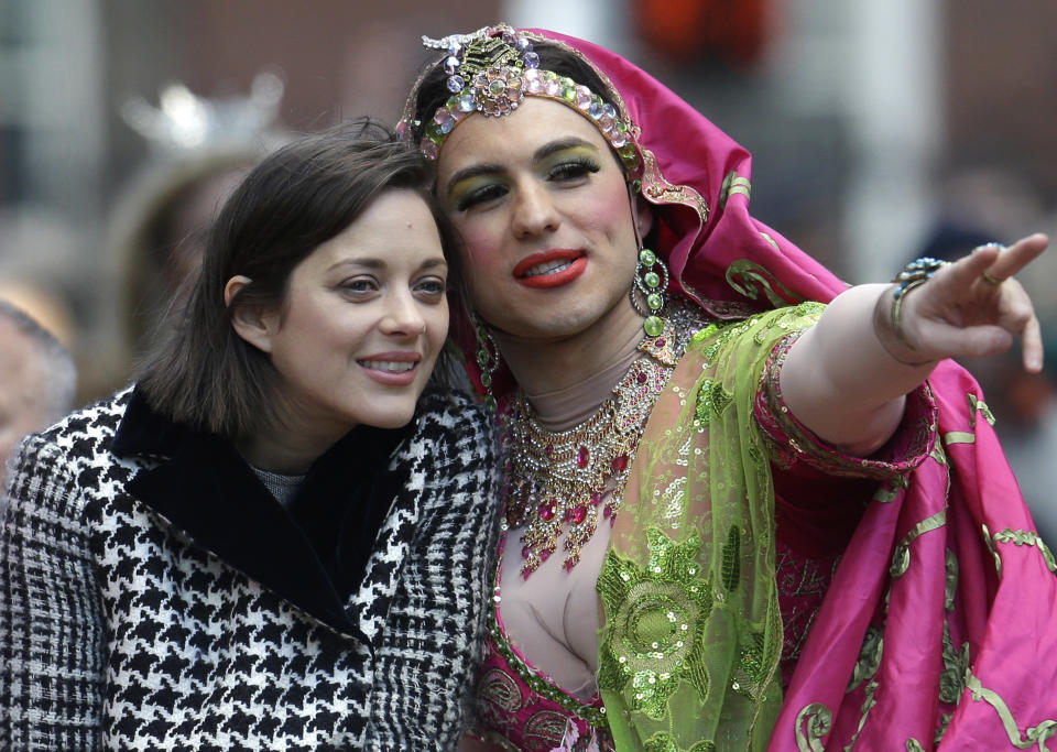 Hasty Pudding Woman of the Year, actress Marion Cotillard, of France, left, rides in the back of a car with Harvard University theatrical student Ben Moss during a parade through Harvard Square, in Cambridge, Mass., Thursday, Jan. 31, 2013. The award was presented to Cotillard by Hasty Pudding Theatricals, a theatrical student society at Harvard University. (AP Photo/Steven Senne)