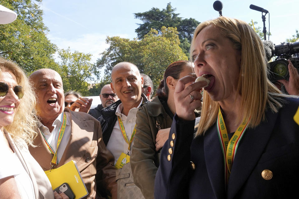 Brothers of Italy leader Giorgia Meloni tastes a piece of mozzarella at the Coldiretti village Italian farmers association's event, in Milan, Italy, Saturday, Oct. 1, 2022. (AP Photo/Luca Bruno)