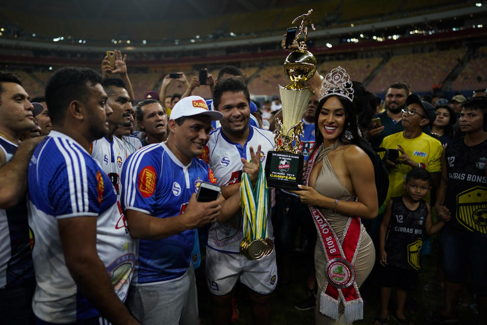 Los jugadores de Alvorada posan con la reina de belleza Isabelle Nogueira, quien sostiene el trofeo que obtuvieron por la ganar en la final del torneo Peladao en la Arena da Amazonia en Manaos, Brasil, el sábado 16 de febrero de 2019. (AP Foto/Víctor R. Caivano)