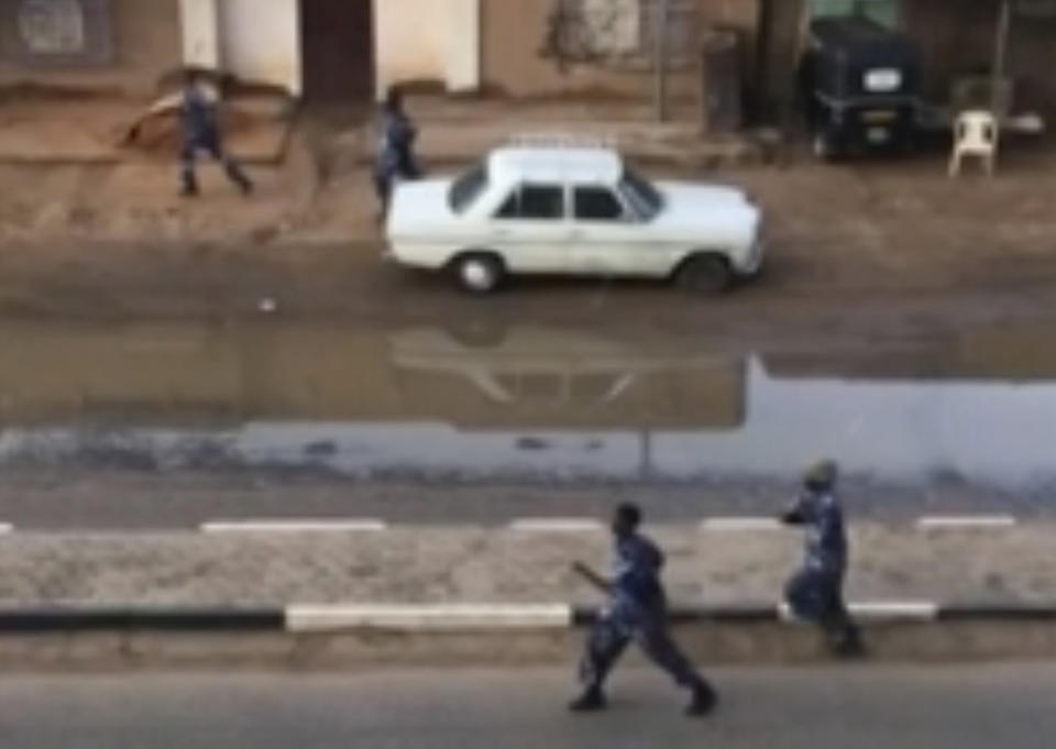 In this image made from video, Police officers running down a street in Khartoum, Sudan, on Monday, June 3, 2019. Sudanese security forces moved against a protest sit-in camp in the capital Monday, witnesses and protest organizers said. Machine gun fire and explosions were heard and smoke rose from the area. Protest organizers said at least two people were killed. (Elmontasir Darwish via AP)