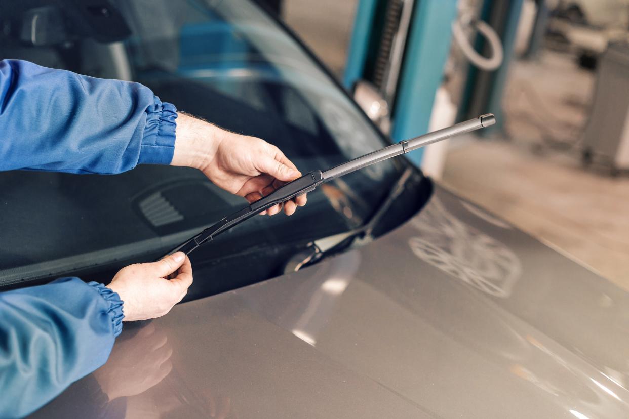 technician is changing windscreen wipers on a car station