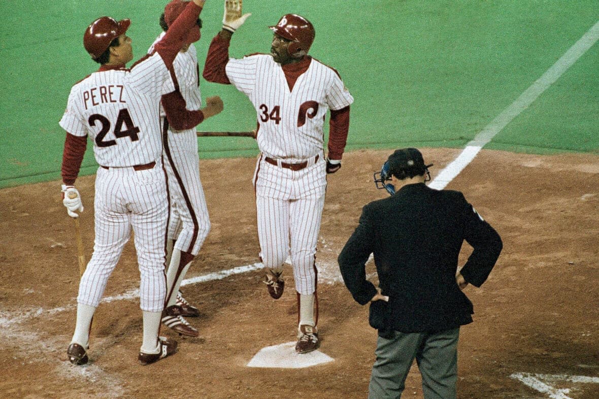 Philadelphia Phillies Gary Matthews (34) is congratulated at home plate by teammate Tony Perez (24) after his second inning solo homer against Baltimore Orioles pitcher Mike Flanigan in Game 3 of the World Series, Friday, Oct. 14, 1983, in Philadelphia. (AP Photo/File)