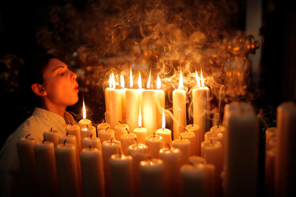 A penitent of “Lagrimas and Favores” blows out candles inside a church on Palm Sunday