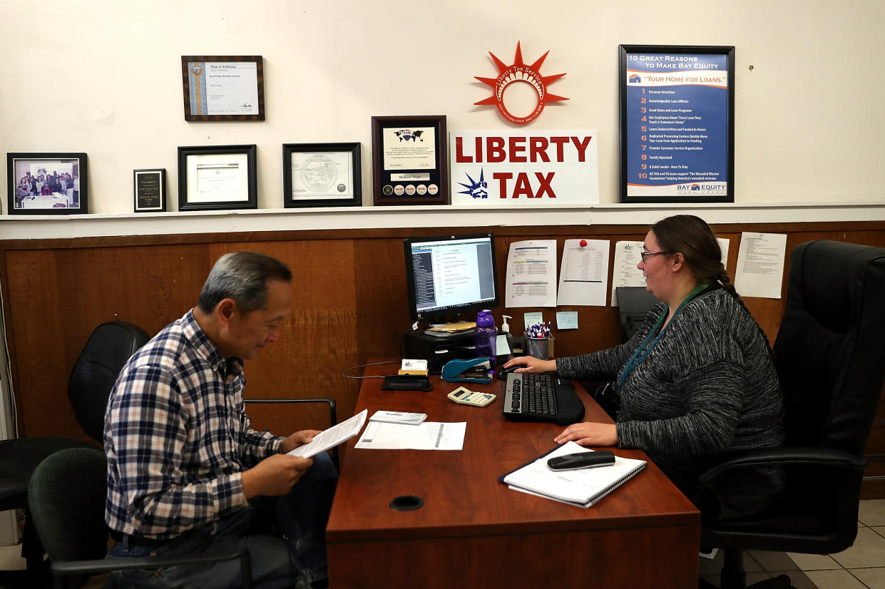 Liberty Tax Service tax specialist Laura Tuuri (R) helps a client do his taxes in Oakland, California. (Credit: Justin Sullivan/Getty Images)