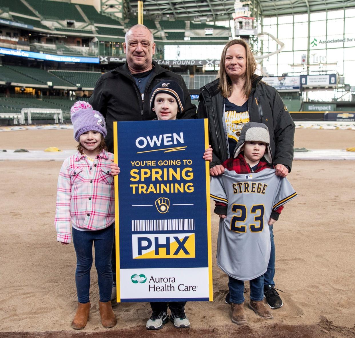 Owen Strege of Algoma holds the ticket given to him by Aurora Health Care to travel with his family as a VIP guest to the Milwaukee Brewers spring training camp in Phoenix to meet Brewers players, tour the locker room and throw out the first pitch at the team's Feb. 25 game. Shown with Owen as he received the news Feb. 18 at American Family Field in Milwaukee are his parents, Kayla and Bill Strege; his brother, Hudson Strege (front right) and sister, Chelsea Strege.