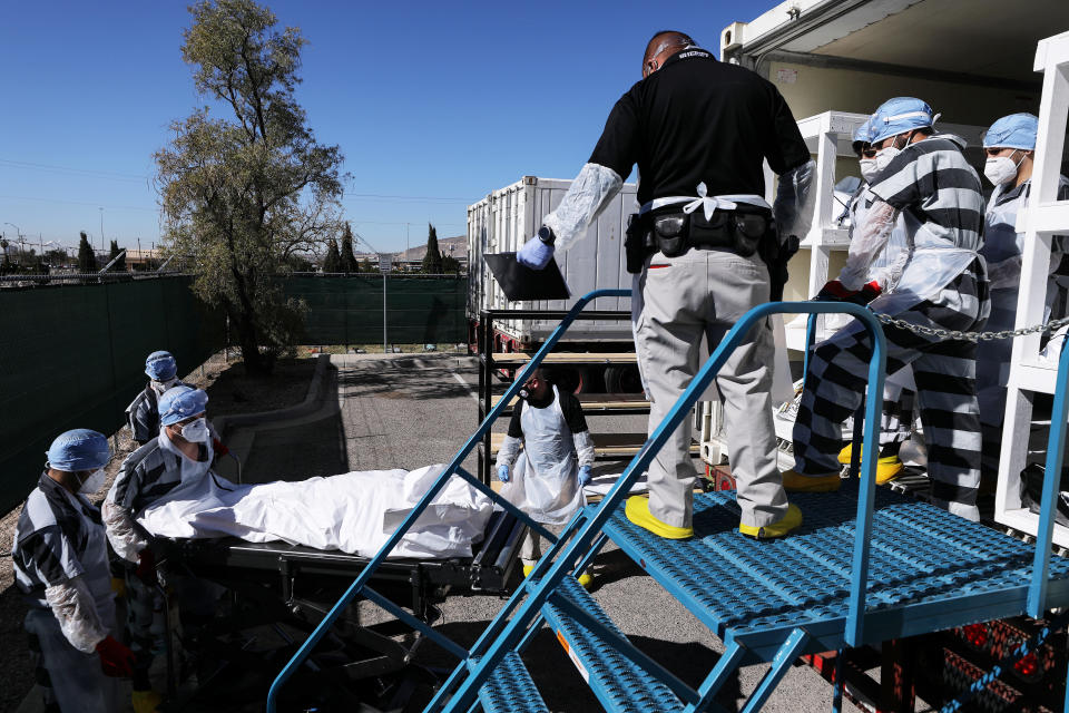 Inmates load bodies into a refrigerated temporary morgue.