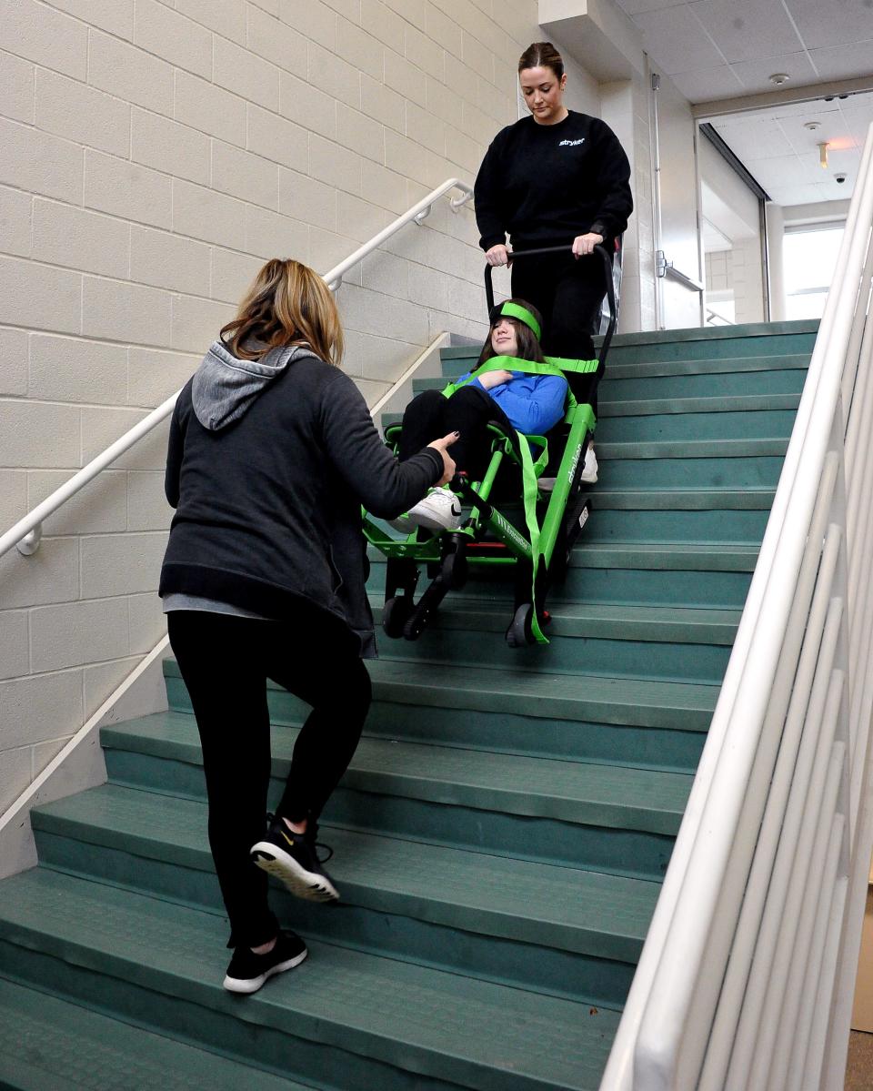 Michelle Stitt and Julia Jurgenson safely transport Makayla Maxwell down a flight of steps.