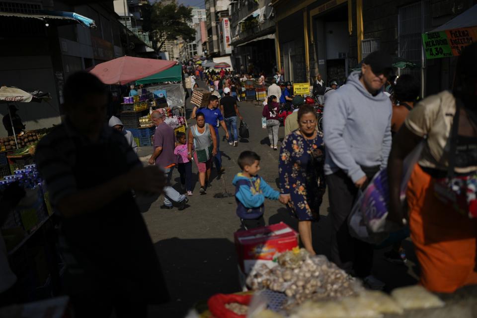People walk past street vendors in Caracas, Venezuela, Tuesday, Feb. 28, 2023. About three-quarters of Venezuelans live on less than $1.90 a day — the international benchmark of extreme poverty. (AP Photo/Ariana Cubillos)