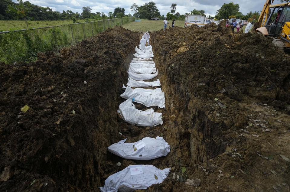 A forensics team bury a group of 15 migrants who died trying to cross the Darien Gap, at the Guayabillo cemetery in Agua Fria, Panama, Thursday, Sept. 30, 2021. The migrants, who are buried with plasticized cards containing what little information investigators were able to gather, die of natural causes or in accidental deaths while crossing the Darien jungle trying to make their way to the United States. (AP Photo/Arnulfo Franco)