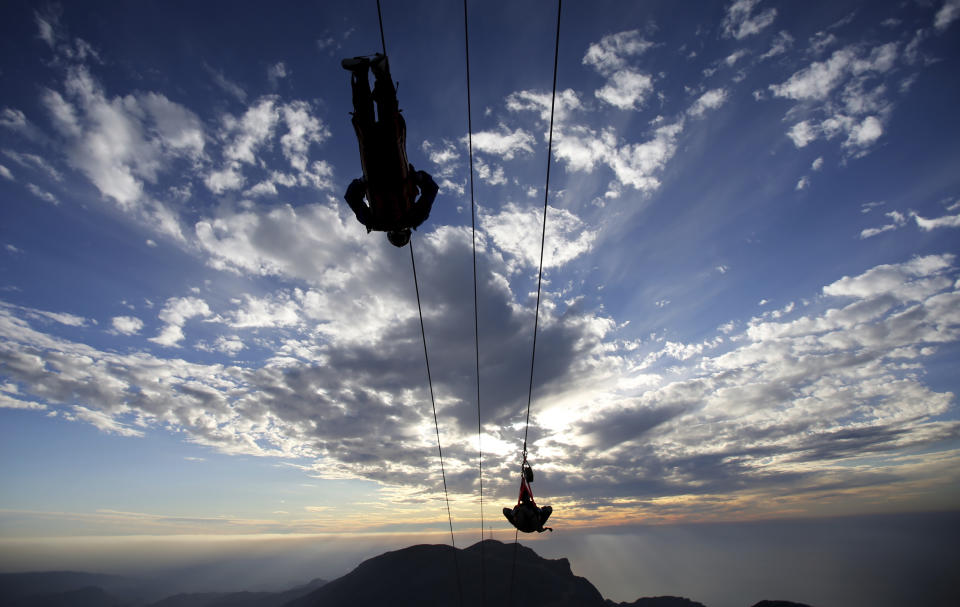 In this Wednesday, Jan. 31, 2018 photo, thrill-seekers try out a new zip line, on the peak of Jebel Jais mountain, 25 kms (15.5 miles) north east of Ras al-Khaimah, United Arab Emirates. The UAE is claiming a new world record with the opening of the world's longest zip line, measuring 2.83 kilometers (1.76 miles) in length. Guinness World Records officials certified the zip line on Thursday, the same day the attraction opened to the public. (AP Photo/Kamran Jebreili)