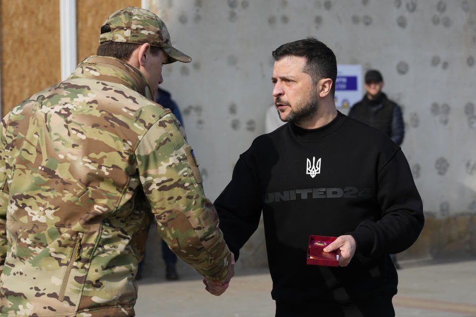 Ukrainian President Volodymyr Zelenskyy presents a medal to a serviceman in Trostianets in the Sumy region of Ukraine, Tuesday March 28, 2023. (AP Photo/Efrem Lukatsky)