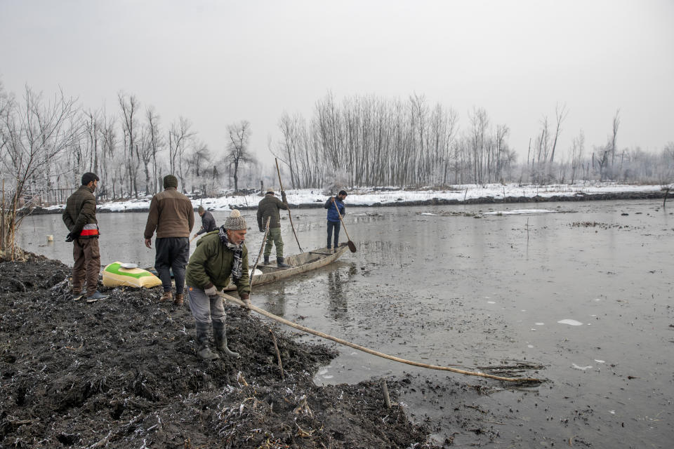 Ghulam Mohiuddin Dar, foreground, breaks ice with other wildlife officials in the frozen surface of a wetland in Hokersar, north of Srinagar, Indian controlled Kashmir, Friday, Jan. 22, 2021. Wildlife officials have been feeding birds to prevent their starvation as weather conditions in the Himalayan region have deteriorated and hardships increased following two heavy spells of snowfall since December. Temperatures have plummeted up to minus 10-degree Celsius (14 degrees Fahrenheit). (AP Photo/Dar Yasin)