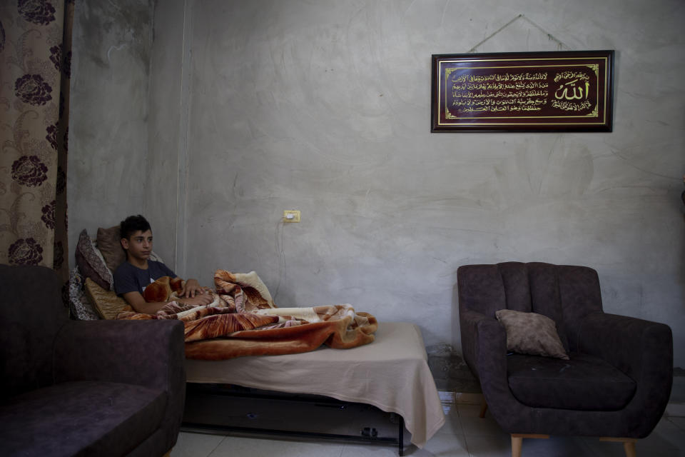 Palestinian youth, Tareq Zubeidi, 15, rests at his house, in the West Bank village of Silat ad-Dhahr, Tuesday, Aug. 31, 2021. Zubeidi says he was abducted and beaten by a group of Israeli settlers after they found him and his friends eating snacks near an evacuated hilltop settlement in the occupied West Bank. More than two weeks after the Aug. 17 incident, he says he can barely walk and is afraid to leave his home. (AP Photo/Majdi Mohammed)