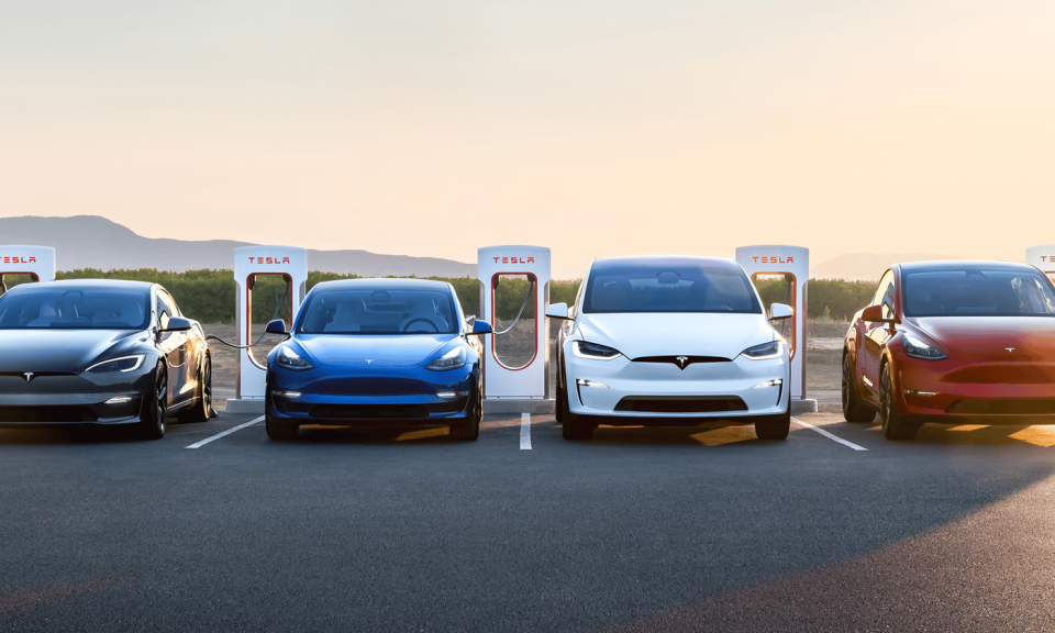 Four Tesla vehicles side-by-side at a charging station.