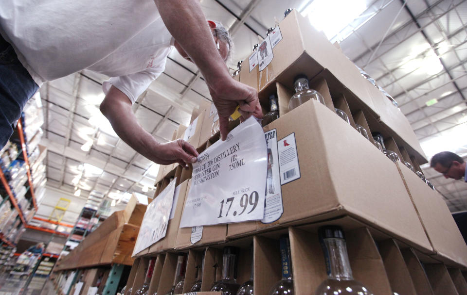 Store wine steward Robert Shelden places price signs on boxes of gin at a Costco warehouse store Friday, June 1, 2012, in Seattle. Private retailers begin selling spirits for the first time under a voter-approved initiative kicking the state out of the liquor business. The initiative allows stores larger than 10,000 square feet and some smaller stores to sell hard alcohol.(AP Photo/Elaine Thompson)