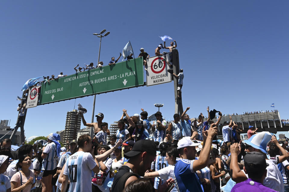 Argentine soccer fans climb on highway signs for a homecoming parade for the Argentine soccer team that won the World Cup tournament in Buenos Aires, Argentina, Tuesday, Dec. 20, 2022. (AP Photo/Mario De Fina)