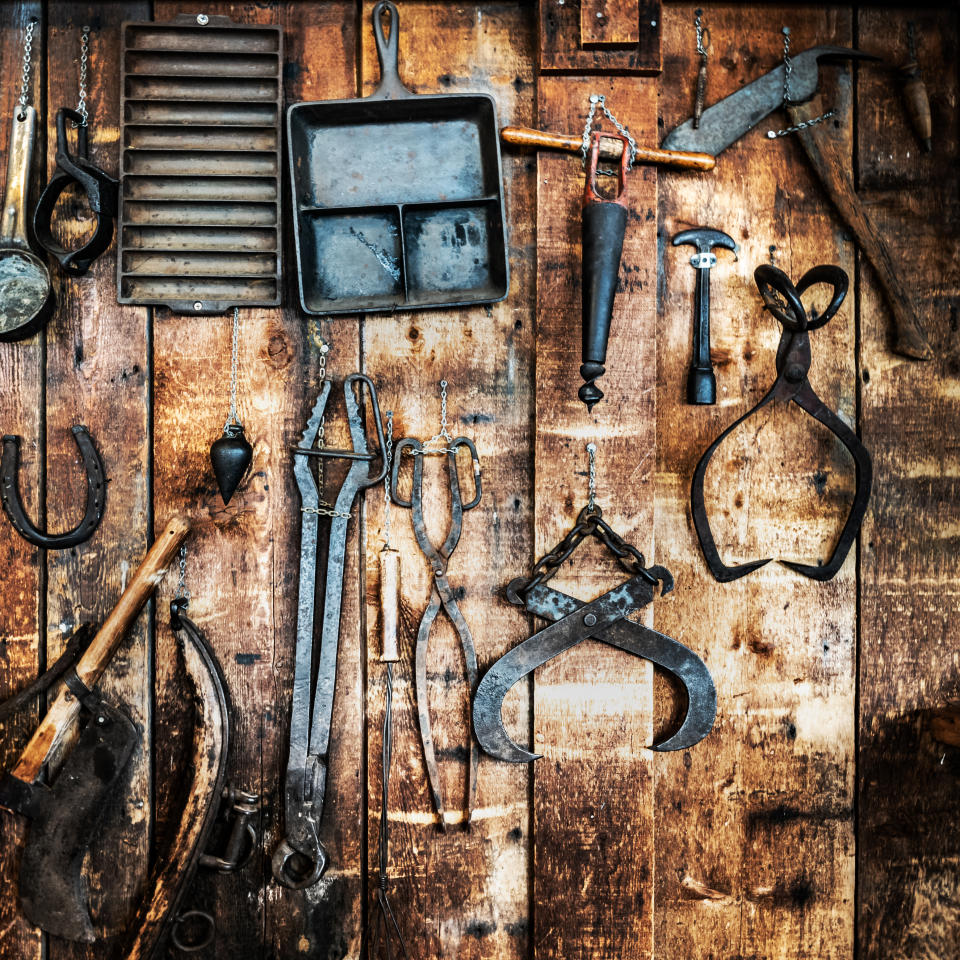 Collection of antique metal tools displayed on a wooden wall