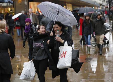 Shoppers walk in wet and windy weather on Oxford Street in central London December 23, 2013. REUTERS/Olivia Harris