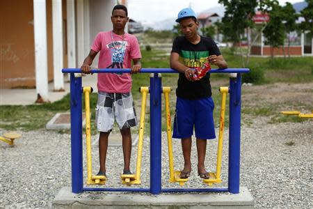 Boys step on public exercise machines in Ciudad Caribia outside Caracas September 19, 2013. REUTERS/Jorge Silva