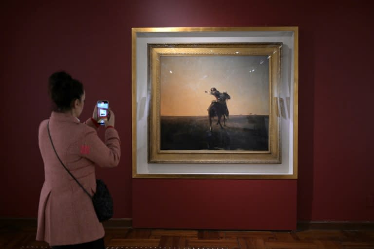 La brasileña Fernanda Vargas Souto fotografía el cuadro "Gaucho en el campo" del pintor uruguayo Juan Manuel Blanes, exhibida en el Museo Nacional de Artes Visuales (MNAV) de Montevideo, el 2 de mayo de 2024 (Eitan ABRAMOVICH)