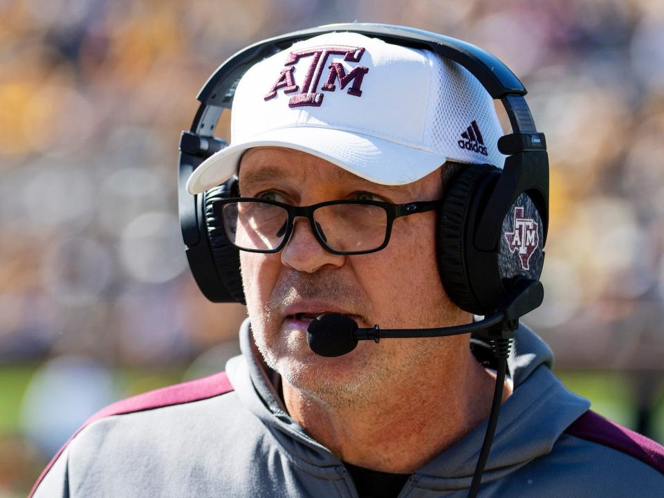 Jimbo Fisher looks on and speaks into a headset during a game in 2021.