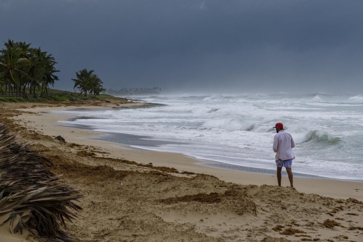 A man walks on the beach next to waves kicked up by Hurricane Fiona in Punta Cana, the Dominican Republic on Monday, Sept. 19, 2022.