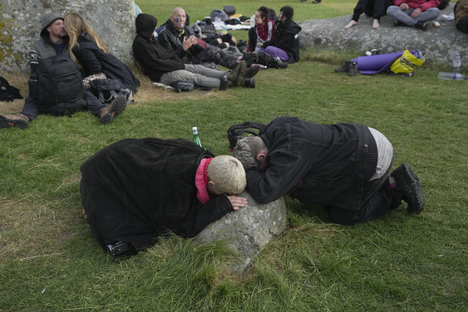 Revelers meditate next to stones at sunrise as thousands gather at the ancient stone circle Stonehenge to celebrate the Summer Solstice, the longest day of the year, near Salisbury, England, Wednesday, June 21, 2023. (AP Photo/Kin Cheung)