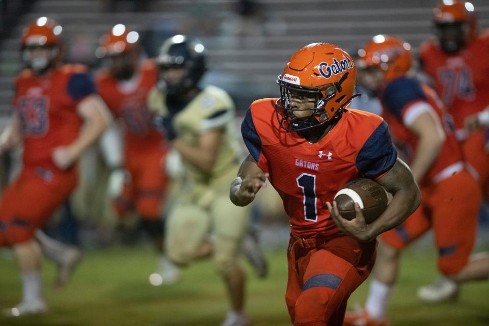 Escambia wide receiver Akeem Stokes (No. 1) turns up field and runs for extra yards against the Gulf Breeze defense during Friday night's rain-soaked game against the Dolphins. 