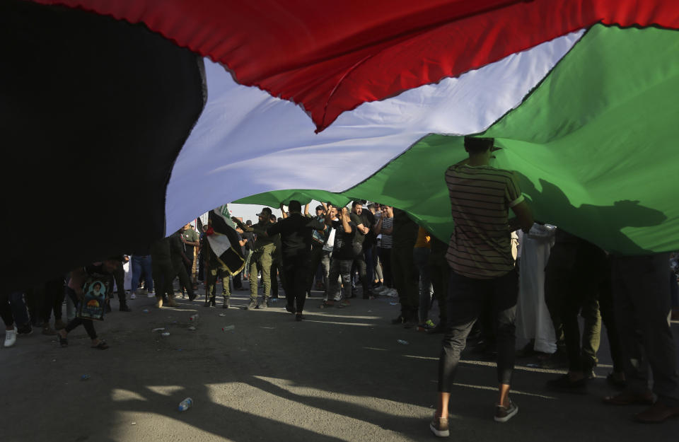 Protesters hold a large Palestinian flag as they gather during a demonstration to show support for Palestinians in Gaza and to condemn Israeli attacks, in Baghdad, Iraq, Thursday, May 20, 2021. (AP Photo/Hadi Mizban)