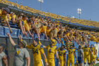 FILE - In this Oct. 6, 2018, file photo, West Virginia players high-five fans after defeating Kansas 38-22 in an NCAA college football game in Morgantown, W. Va. The crippling coronavirus pandemic has brought the entire world — including the sports world — to a standstill, and it shows no sign of going away anytime soon. That has left fans, stadium workers, team owners, sponsors and yes, even players, wondering what life will be like when games finally resume. (AP Photo/Craig Hudson, File)