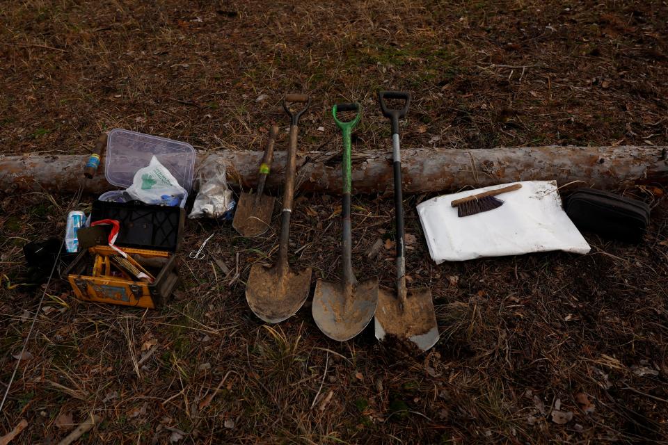 Shovels and other tools are seen laid out on the ground.