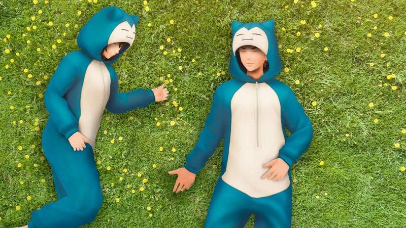 Two Pokemon Go players wearing Snorlax onesies sleep on a bed of grass.