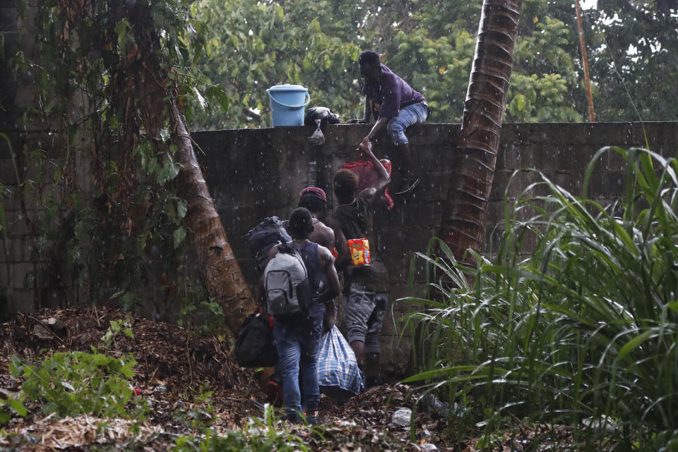 En esta imagen del 29 de mayo de 2019, migrantes haitianos trepan el muro del recinto ferial Mesoamericana en Tapachula, en el estado mexicano de Chiapas. (AP Foto/Marco Ugarte)