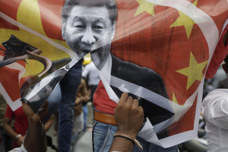 A Karni Sena supporter tears a banner featuring Chinese President Xi Jinping and shout slogans during a protest against China in Ahmedabad, India, Wednesday, June 24, 2020. Chinese and Indian military commanders have agreed to disengage their forces in a disputed area of the Himalayas following a clash that left at least 20 soldiers dead, both countries said Tuesday. The commanders reached the agreement Monday in their first meeting since the June 15 confrontation, the countries said. (AP Photo/Ajit Solanki)