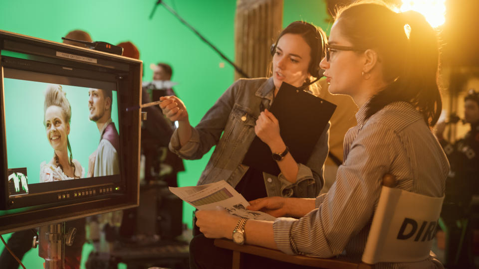 Two film crew members review footage on set. Their expressions indicate focus and collaboration