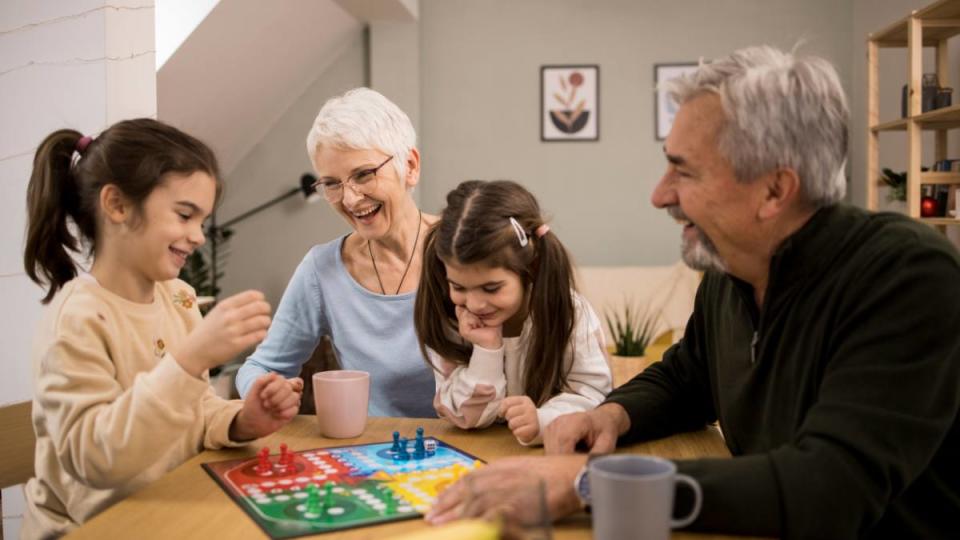 Work from home sales jobs: Two little sisters playing a board game with their grandma and grandpa.