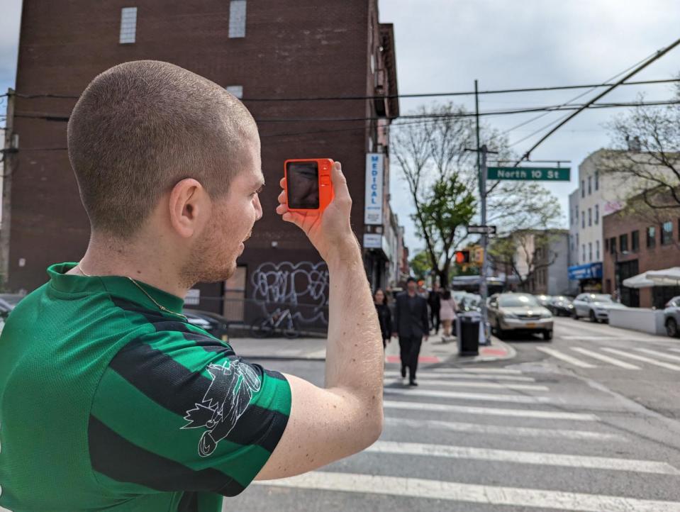 PHOTO: Artist Danny Cole tests his Rabbit R1 on a street corner, April 30, 2024, in Brooklyn, NY (Michael Dobuski/ABC News)