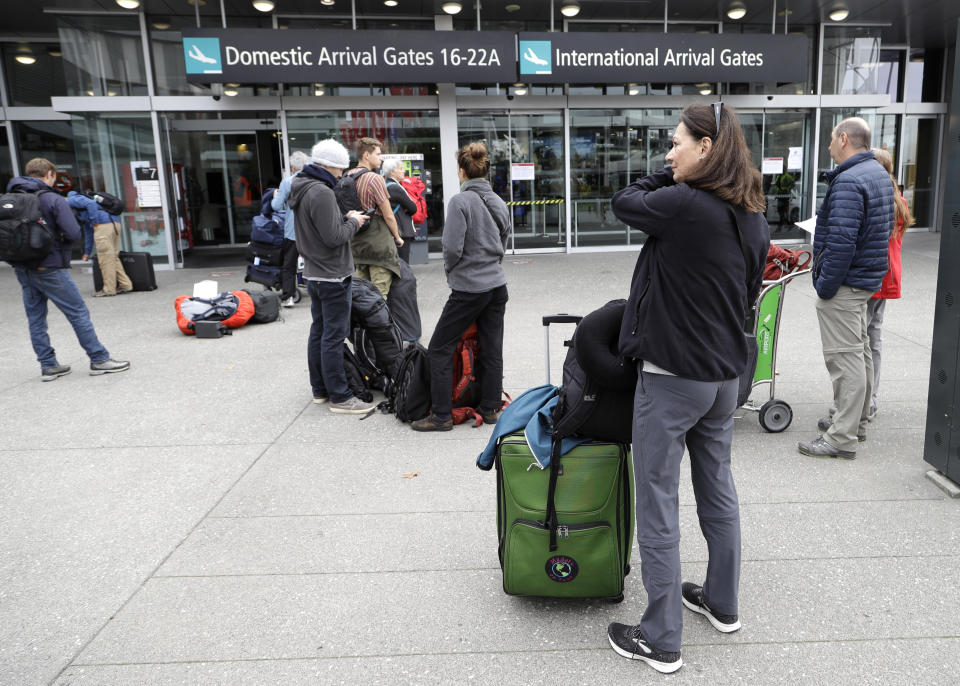 Foreign tourists line up outside the Christchurch Airport terminal as they prepare to check in for a charter flight back to Germany via Vancouver from Christchurch, New Zealand, Monday, April 6, 2020. The German Embassy in Wellington last week said more than 12,000 German tourists had signed up for its repatriation program from New Zealand following the strict monthlong lockdown, which is aimed at preventing more coronavirus infections. The new coronavirus causes mild or moderate symptoms for most people, but for some, especially older adults and people with existing health problems, it can cause more severe illness or death. (AP Photo/Mark Baker)