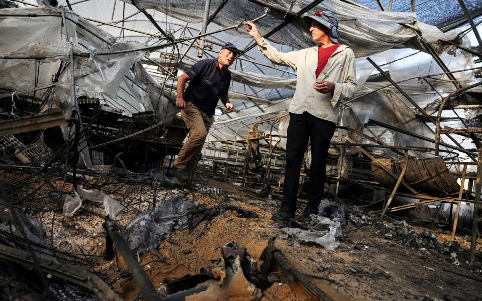 Amit and Moti Dagan, farmers from Ashkelon, stand in their damaged large greenhouse following intense rocket attacks from Gaza Strip into Israel in recent days, in Ashkelon, southern Israel, October 14, 2023.