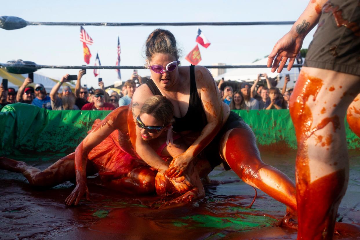 Mariah Garland, left, and Jennifer Justice, right, compete in Sauce Wrestling as referee Johnny Morton keeps an eye on things during the Memphis in May World Championship Barbecue Cooking Contest at Tom Lee Park in Downtown Memphis on May 17, 2023.