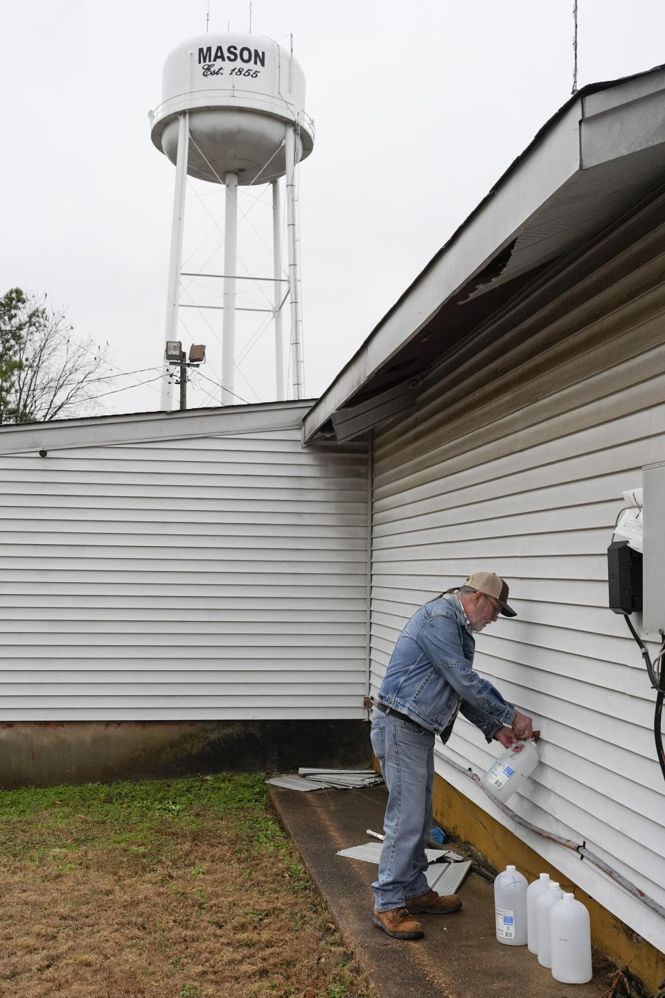 Larry Camper fills water jugs Wednesday, Jan. 24, 2024, in Mason, Tenn. A winter storm brought sub-freezing temperatures and snow to Mason and the rest of Tennessee last week. The cold caused the town's pipes to freeze over and break, creating leaks that lowered water pressure. The cold exposed major problems with a water system that dates back to the 1950s. (AP Photo/George Walker IV)